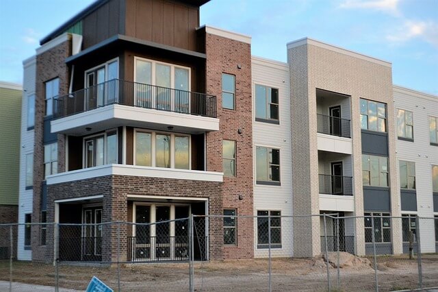 Newly built multifamily building standing behind a construction fence